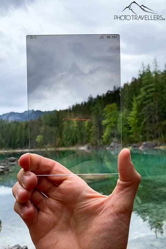 Um filtro de graduação Lee na força 0.9 soft, segurado em uma mão diante de um lago de montanha