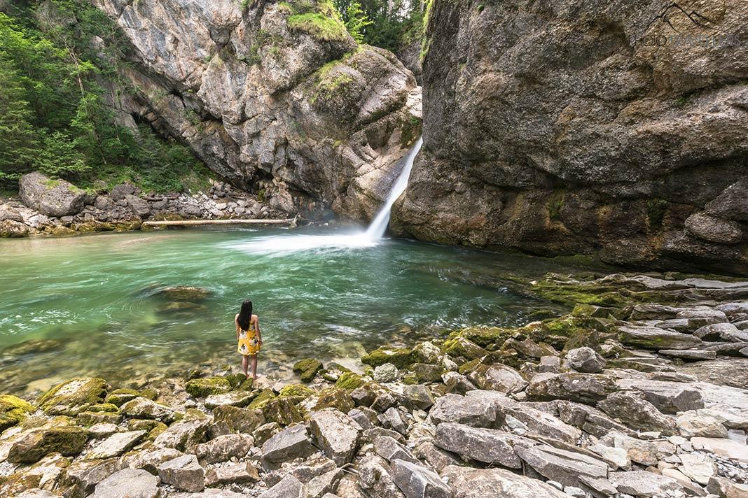 A blogueira de viagem Biggi Bauer em um vestido amarelo nas Cataratas Buchenegger no Allgäu