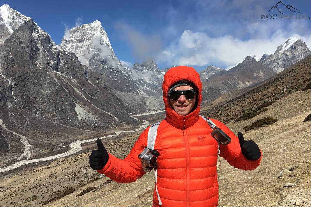 Blogueur de voyage Florian Westermann en doudoune orange dans une vallée de haute altitude au Népal, avec des montagnes en arrière-plan