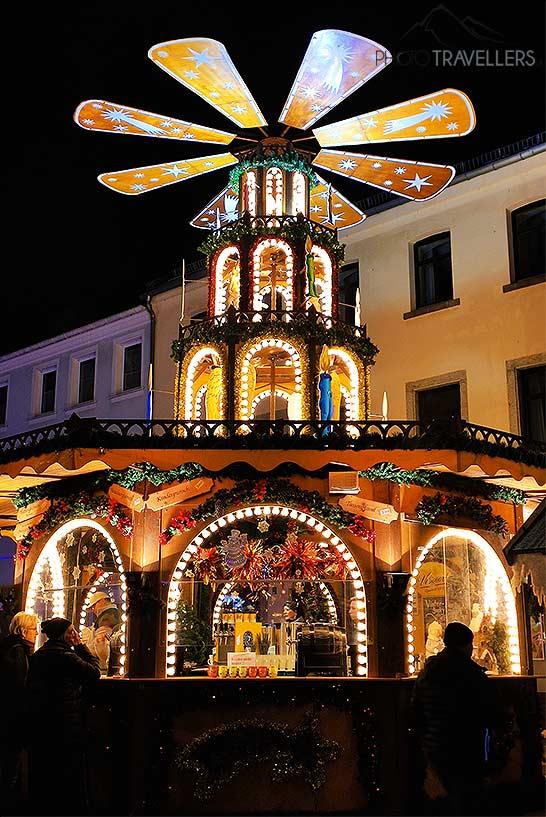 Un stand décoré comme un moulin à vent sur le marché de Noël de Hof avec des visiteurs au premier plan.