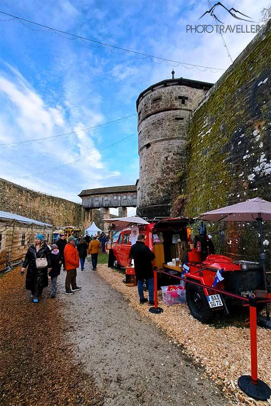 Autour des tours de protection en pierre et des murs de la forteresse de Rosenberg, des visiteurs flânent le long des stands de Noël.