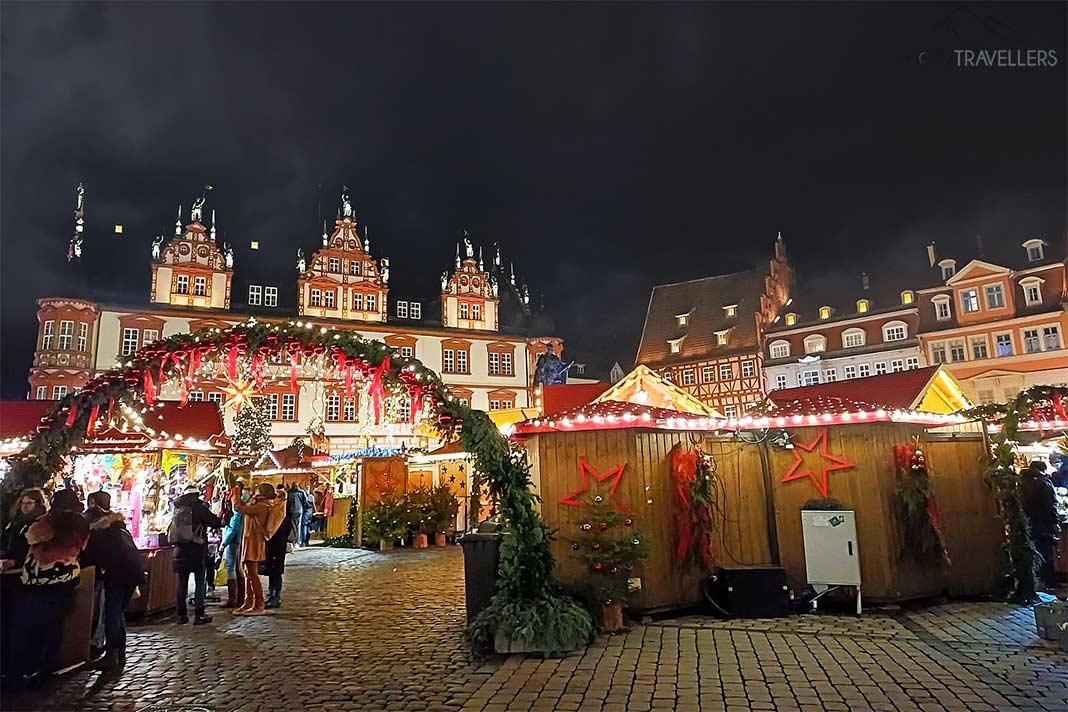 Devant les façades historiques de la place du marché de Cobourg, de nombreuses personnes se tiennent devant les stands de Noël.