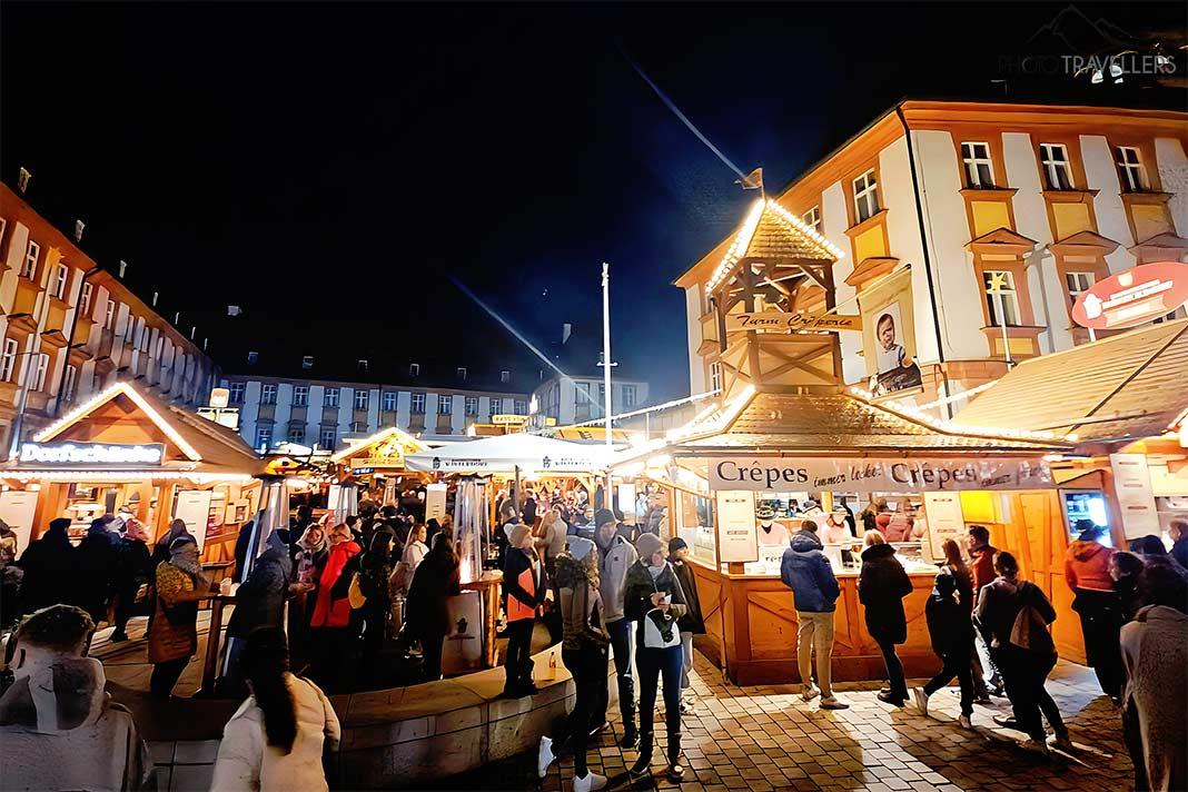 Devant le vieux château illuminé à Bayreuth, les visiteurs font la queue aux stands de Noël.
