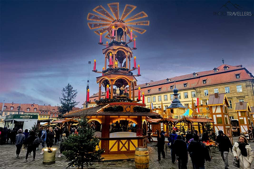 De nombreuses personnes se regroupent autour des stands près du moulin à Noël aux multiples étages sur le marché de Noël de Bamberg.