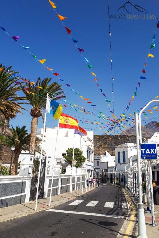 Vista de una calle con banderines y casas de pescadores blancas en Agaete
