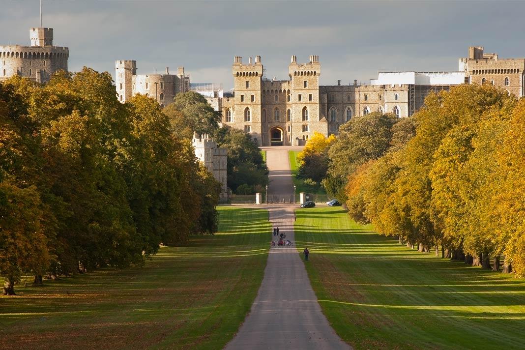 Vue d'un long chemin menant directement au château de Windsor en Angleterre avec des arbres jaunes d'automne