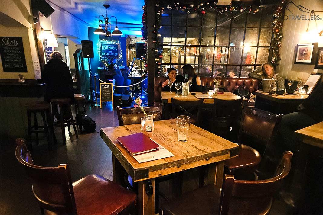 Des tables et chaises en bois avec des gens caractérisent l'intérieur du Hoop and Grapes