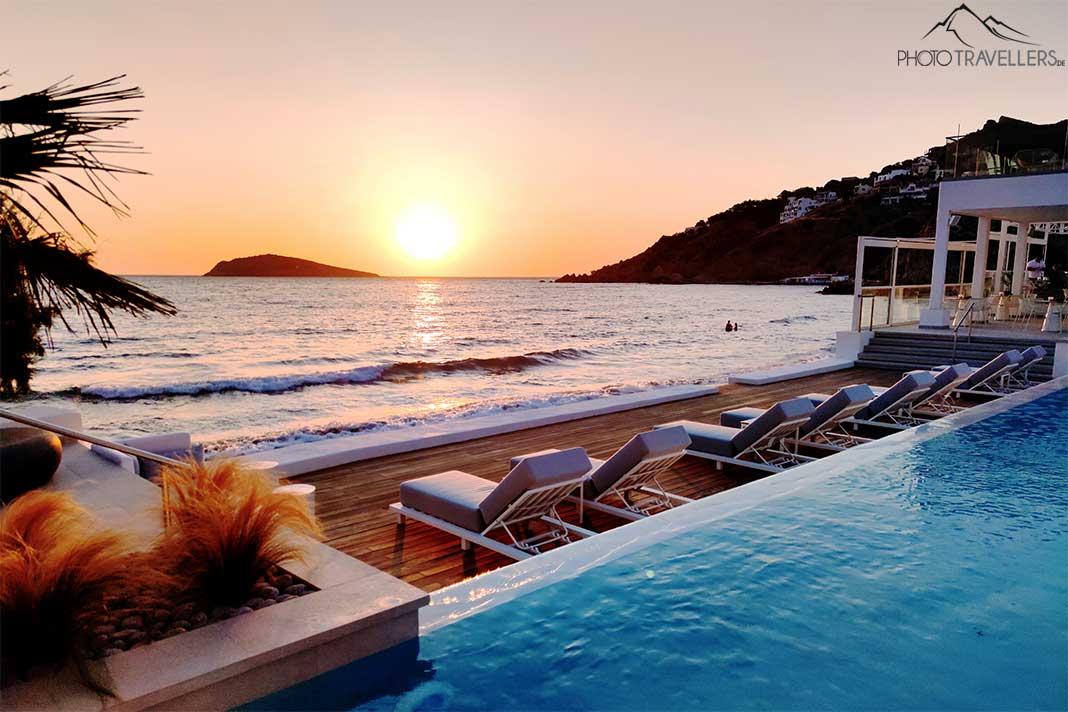 Espreguiçadeiras e piscina do Kantouni Beach Boutique Hotel ao pôr do sol