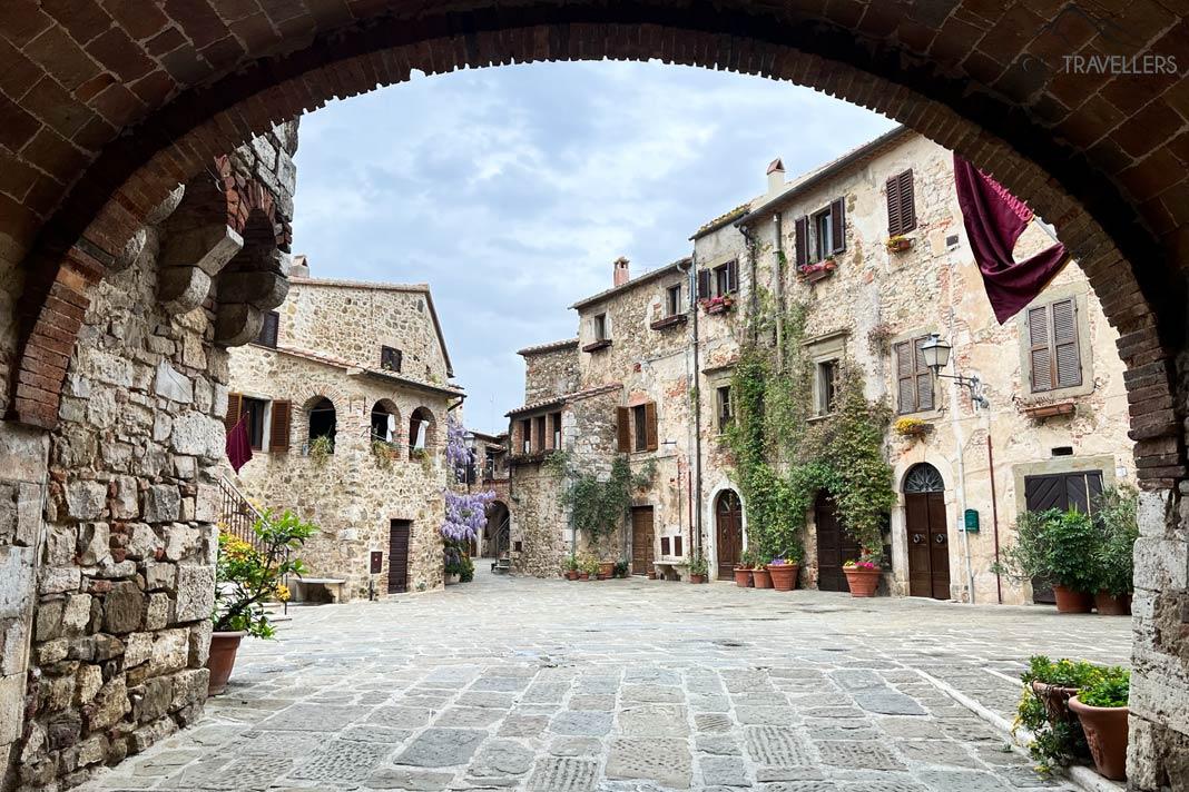 Un arco con vista a una hermosa plaza en Montemerano