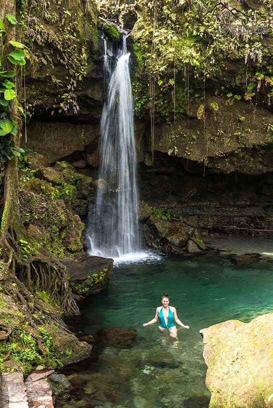 A blogueira de viagens Biggi Bauer com um maiô verde na água da Piscina de Esmeralda em Dominica