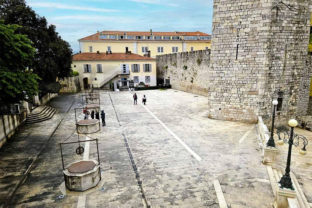 Des visiteurs s'éloignent de la place des Cinq-fontaines près de la Tour du capitaine
