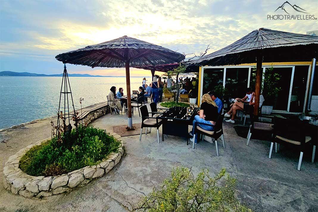 Des gens s'assoient sur la promenade en bord de mer dans un café
