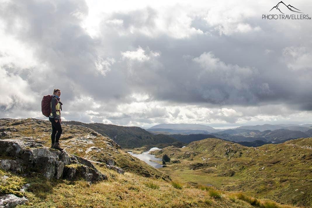 A influenciadora de viagem Biggi Bauer em uma trilha na Noruega em uma paisagem montanhosa impressionante com um lago