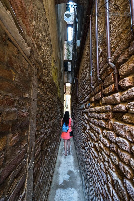 Blogueuse de voyage Biggi Bauer dans une petite robe rose dans la Calle Varisco, la rue la plus étroite de Venise