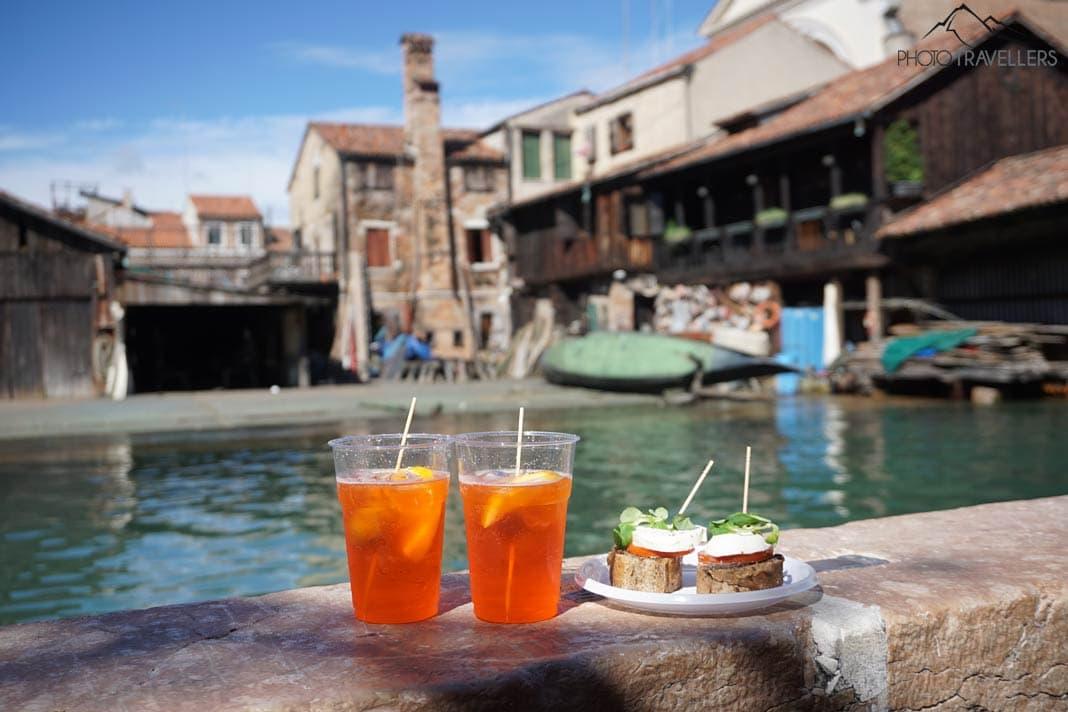 Deux Aperol Spritz et un en-cas sur un mur, derrière l'ancien atelier de gondoles Squero di San Trovaso