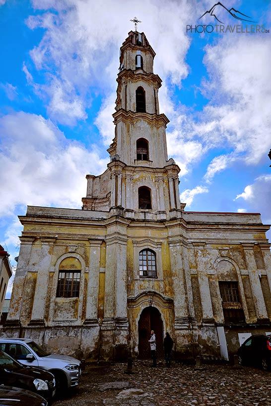 Carros estão estacionados em frente a uma antiga igreja em Vilnius