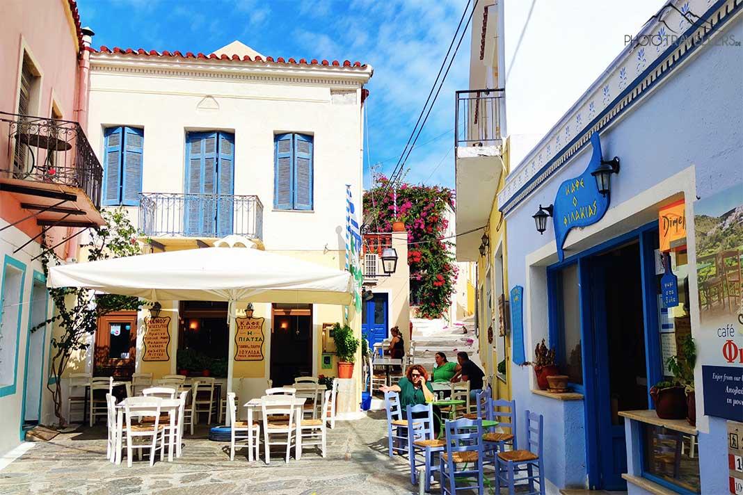 Poucas pessoas sentadas nas mesas externas de uma taverna