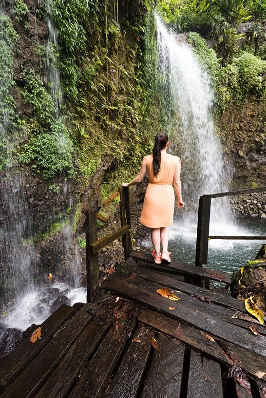 Bloguera de viajes Biggi Bauer en un vestido en la plataforma frente a las Sultan Falls en Dominica