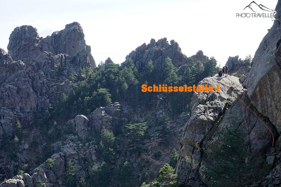 Três caminhantes na rocha diante do ponto chave na trilha nas Aiguilles de Bavella