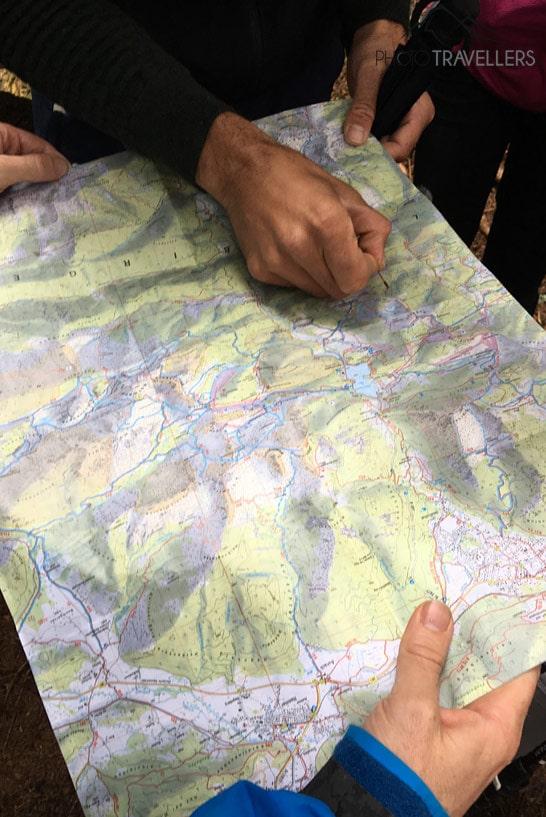 Des mains marquent un chemin sur une carte de randonnée des Alpes