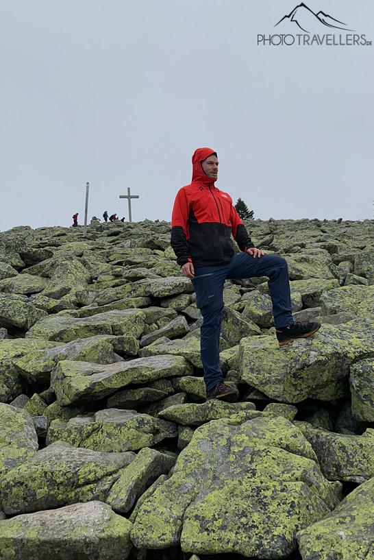 Le blogueur de voyage Florian Westermann portant une veste rouge et regardant sur la mer de blocs au Lusen au loin