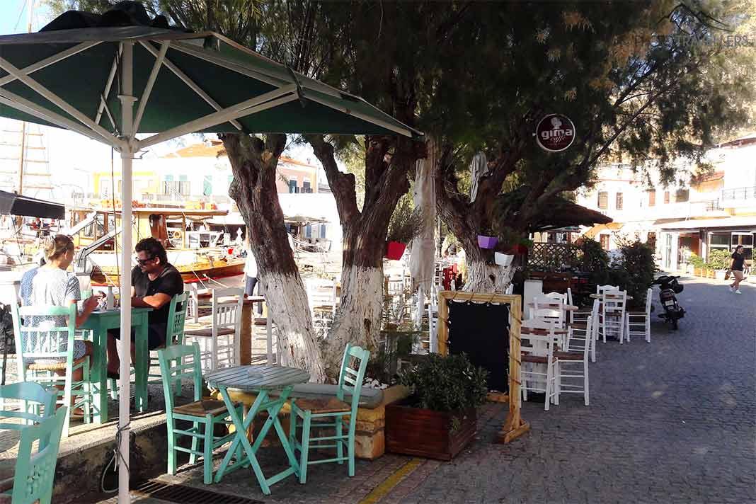 Tables et chaises avec quelques personnes au port d'Agia Marina