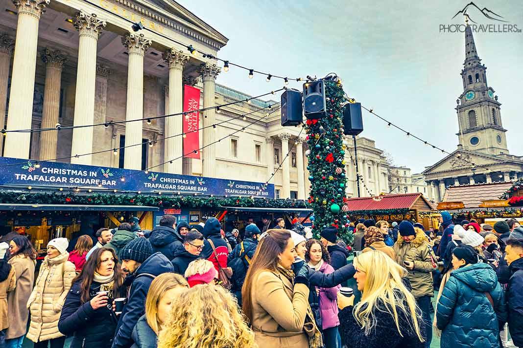 Muitas pessoas se reúnem no mercado de Natal em frente à entrada da National Gallery