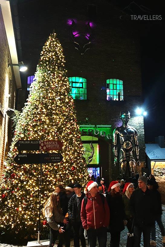 Pessoas com gorros vermelhos de Natal ao lado de uma grande árvore de Natal no Camden Market