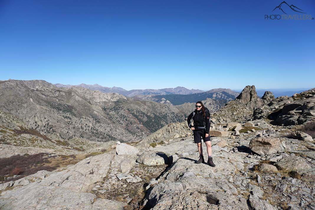 Blogueuse voyage Biggi Bauer sur une dalle de roche, derrière, les montagnes corses