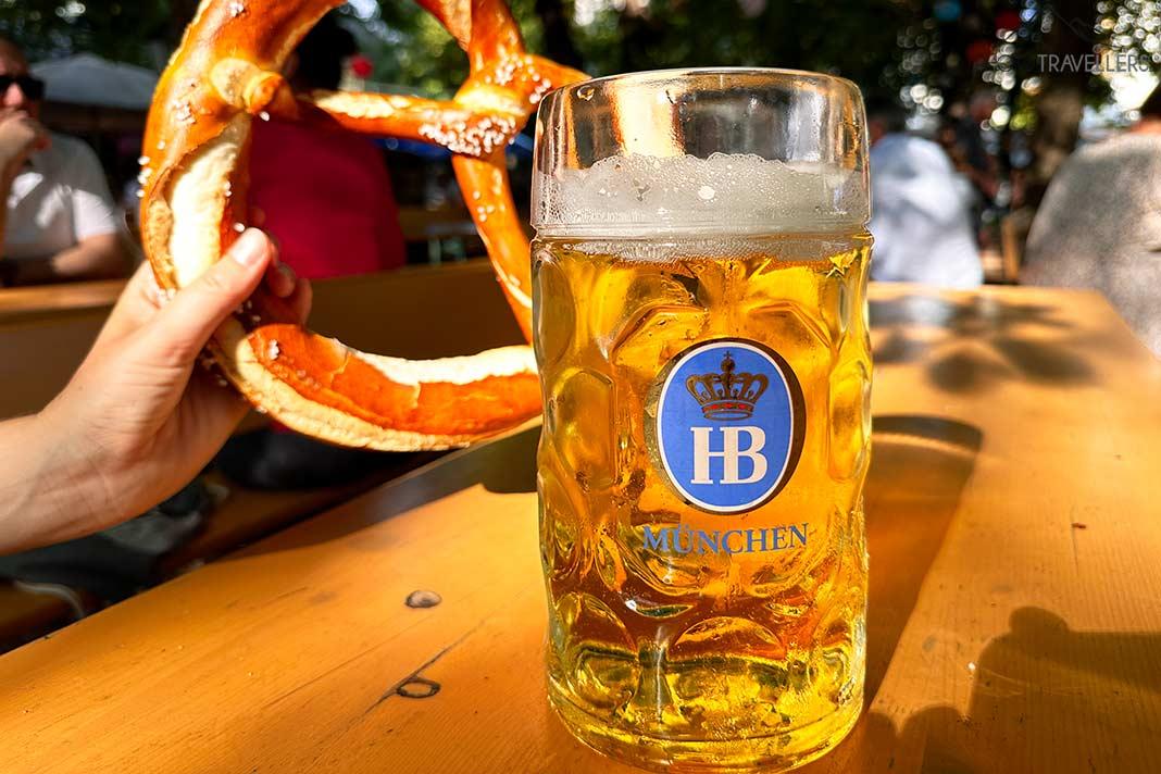 Un pretzel y una jarra de cerveza en un banco de biergarten