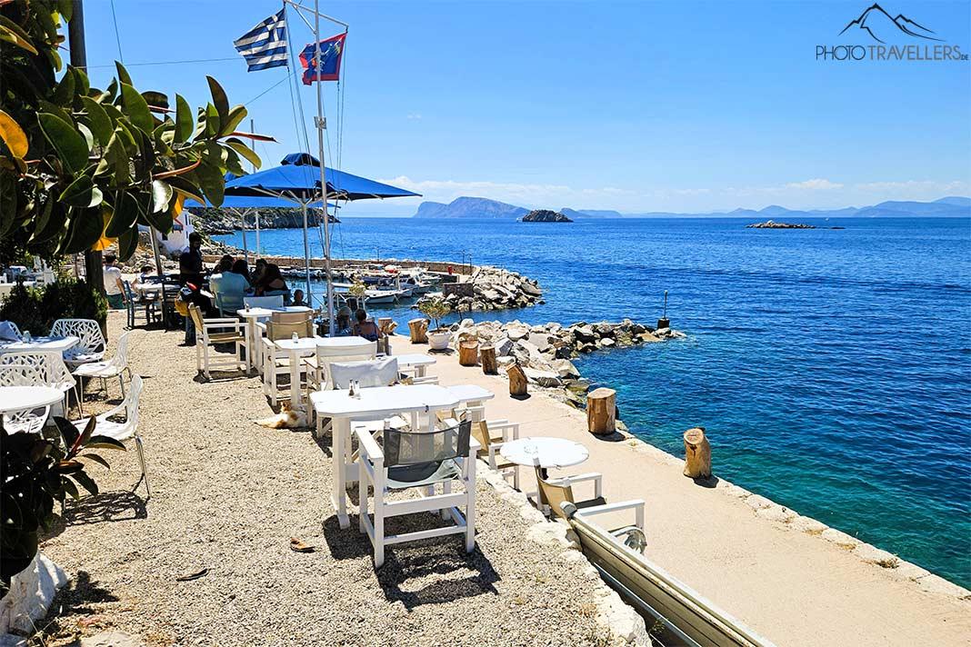 Des tables et des chaises blanches d'une taverne bordent la promenade de Kaminia