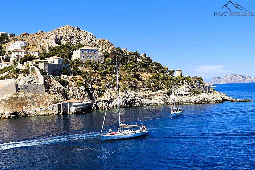 Deux voiliers naviguent dans l'entrée du port d'Hydra avec leurs falaises coniques en arrière-plan