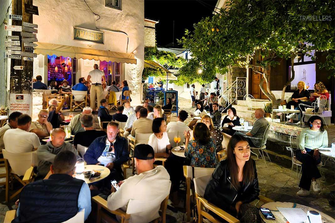 De nombreuses personnes se rassemblent la nuit devant les bars dans les ruelles étroites de la vieille ville d'Hydra