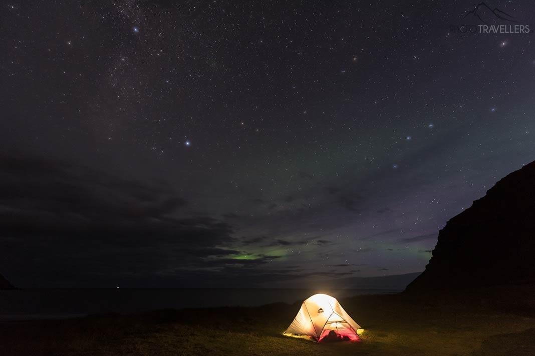 Une tente illuminée la nuit sous les aurores boréales en Islande