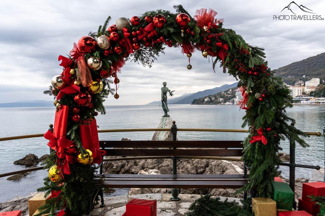 A estátua "Menina com gaivota" em Opatija com guirlanda de Natal