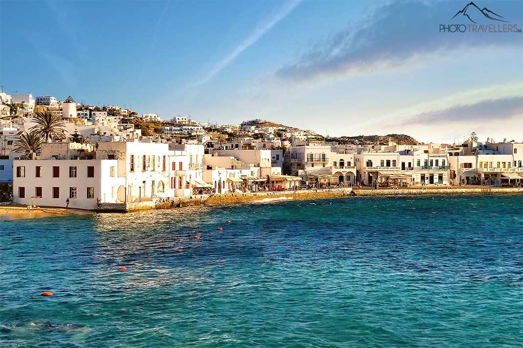 Les maisons blanches de la promenade de la plage de Mykonos forment un beau contraste avec l'eau bleue et le sable doré