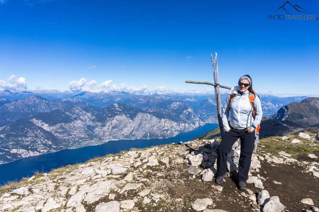 A blogueira de viagem Biggi Bauer em uma pequena cruz de cume no Monte Baldo com vista para o Lago de Garda
