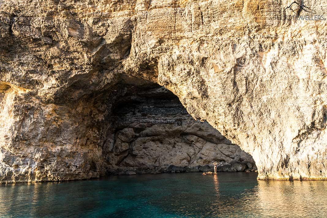 Uma jovem está em uma pedra em uma das cavernas em Comino