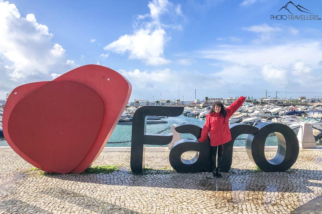 Anita delante del letrero de Faro en el puerto de Faro