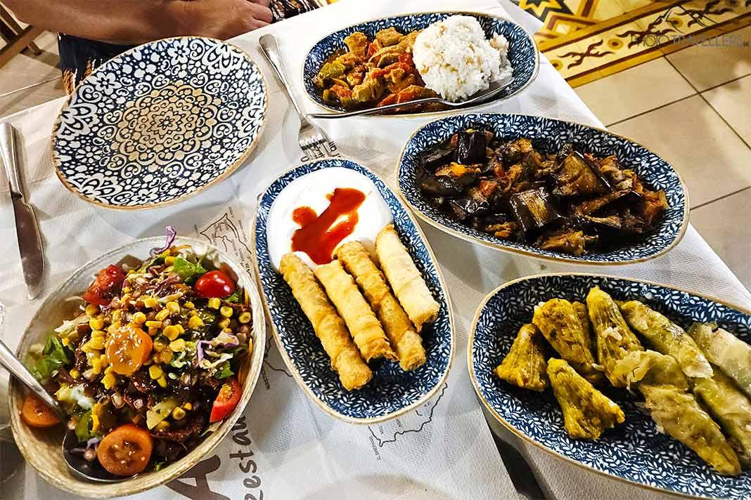 Vários pratos com diferentes comidas gregas estão em uma mesa