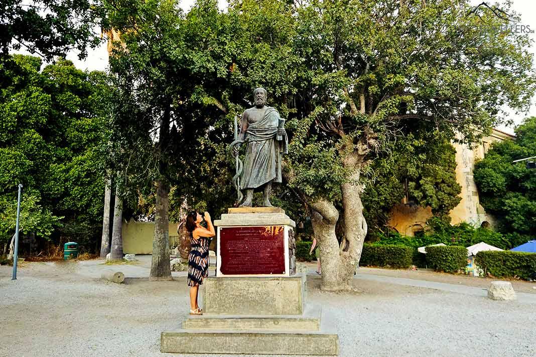 Une femme prie devant la statue d'Hippocrate près de l'arbre éponyme