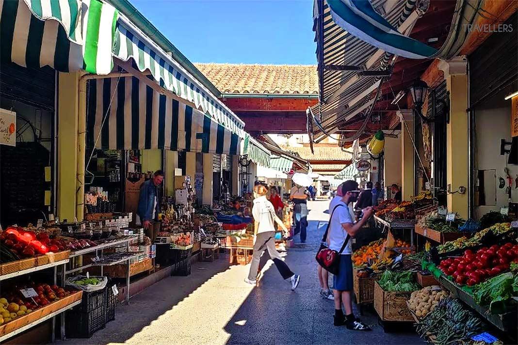 Pessoas estão em pé nas barracas do mercado de alimentos em Corfu