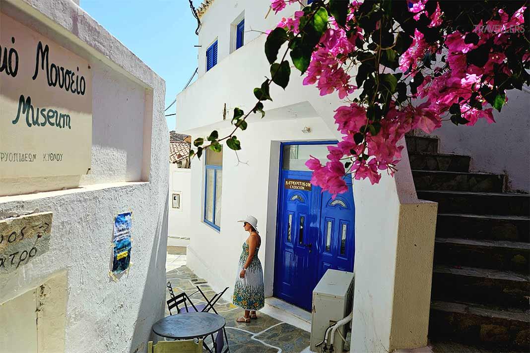 Casas brancas com portas azuis e bougainvilleas rosas em Dryopida