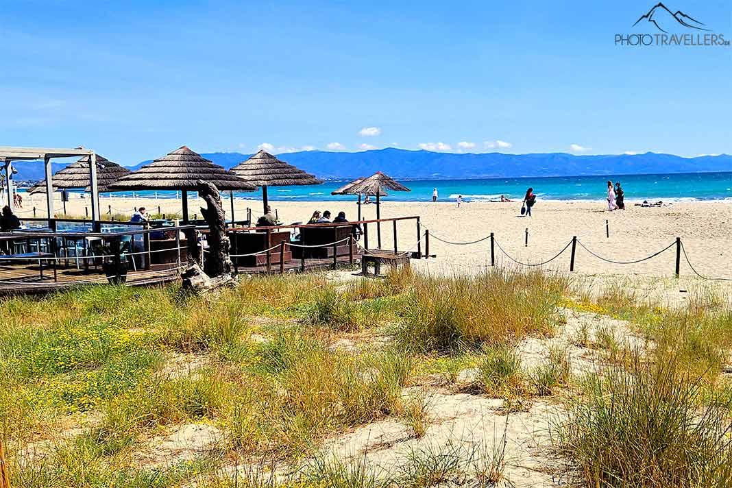 Des clients s'asseyent sous les parasols d'une plage bar sur la plage de sable Poetto