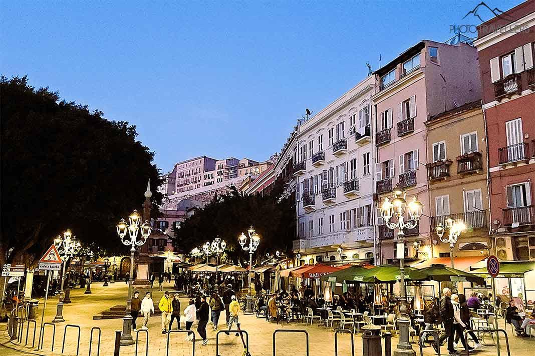Une place sous les arbres avec de nombreux bars sous un ciel nocturne