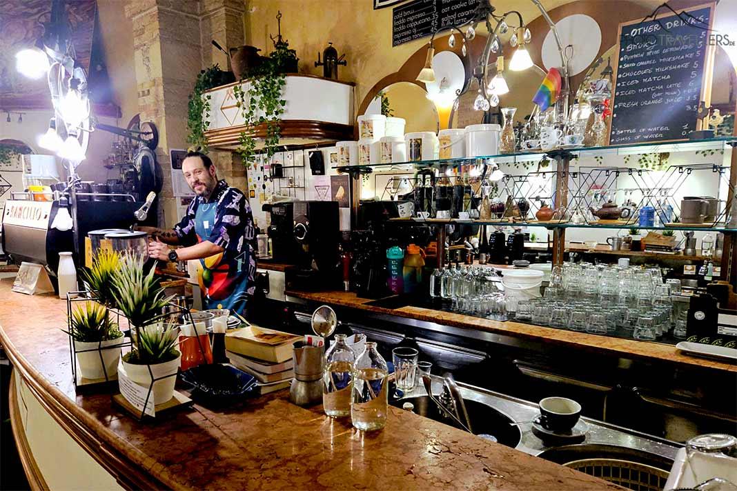 Un homme au bar du Caffé dell'Arte sourit à l'appareil photo