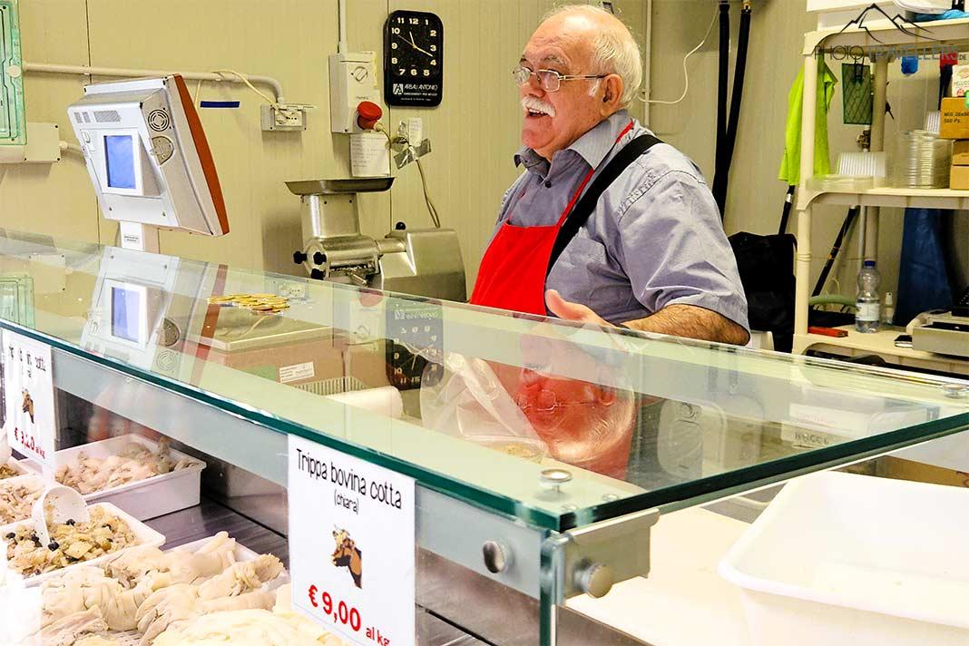 Un vendeur âgé se tient derrière son étal de poissons et sourit