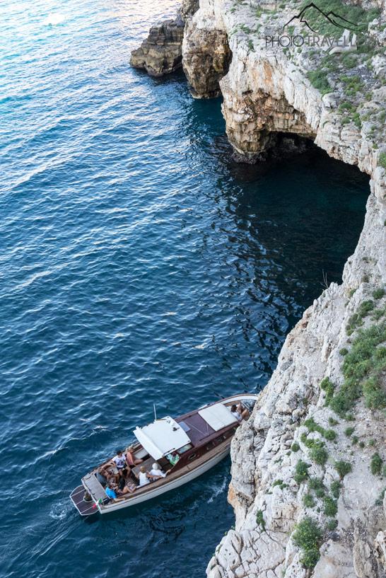 Un bateau devant une grotte en dessous de Polignano a Mare