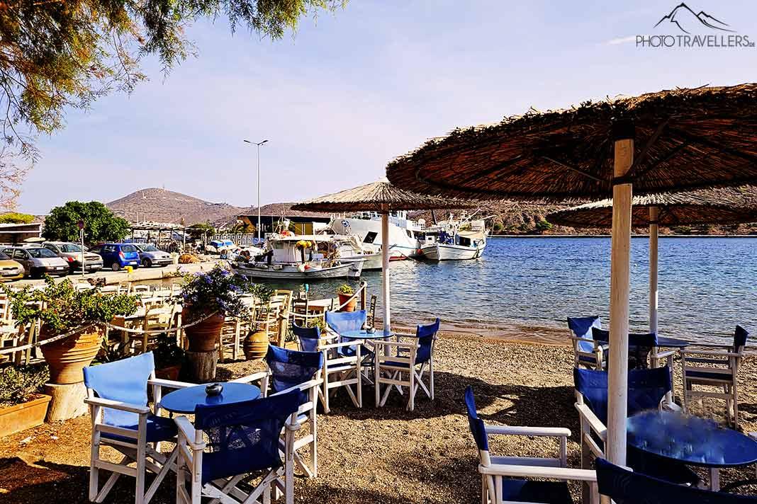 Mesas y sillas vacías en la arena del puerto de Skala en Patmos