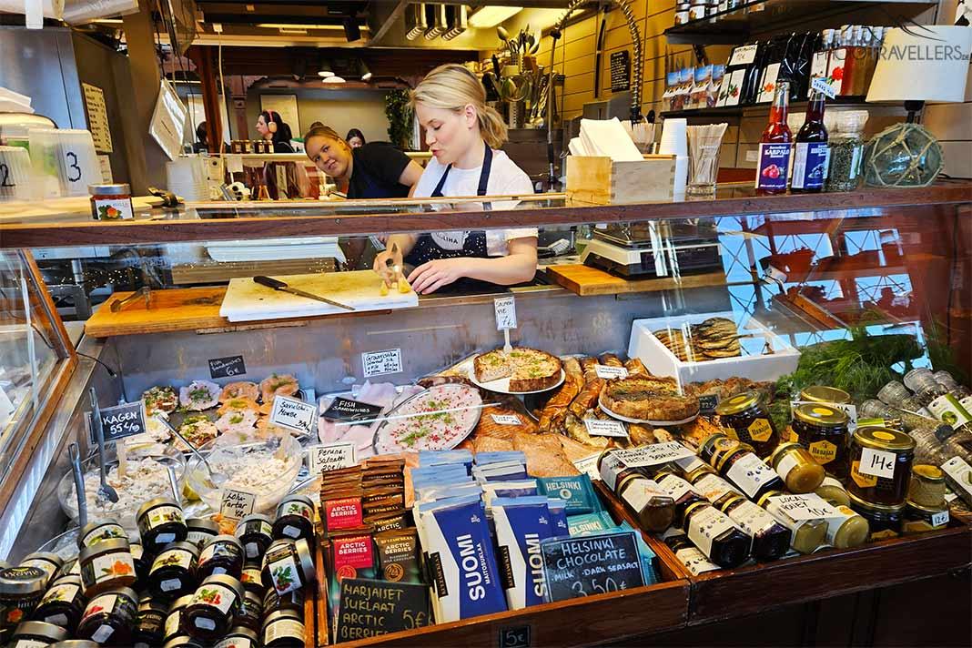 Une vendeuse blonde prépare des délices gastronomiques à son stand dans le marché couvert d'Helsinki.